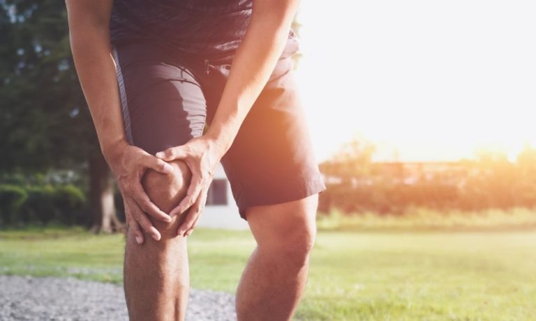 Caucasian male runner holding knee expressing pain